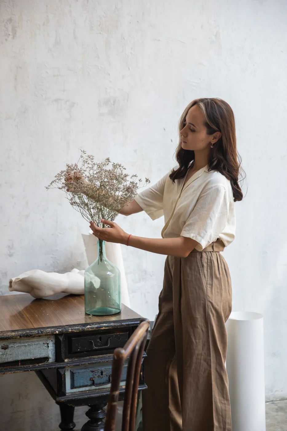 Loose light blouse and wide brown trousers.