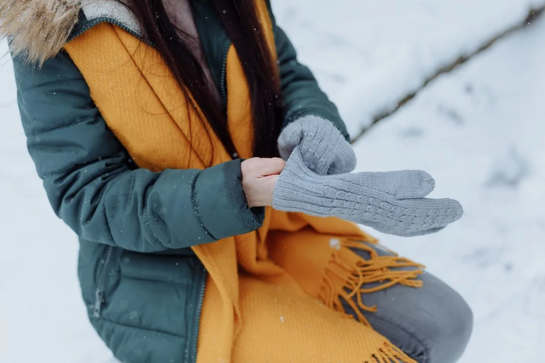 Grey gloves, yellow scarf and green winter jacket.