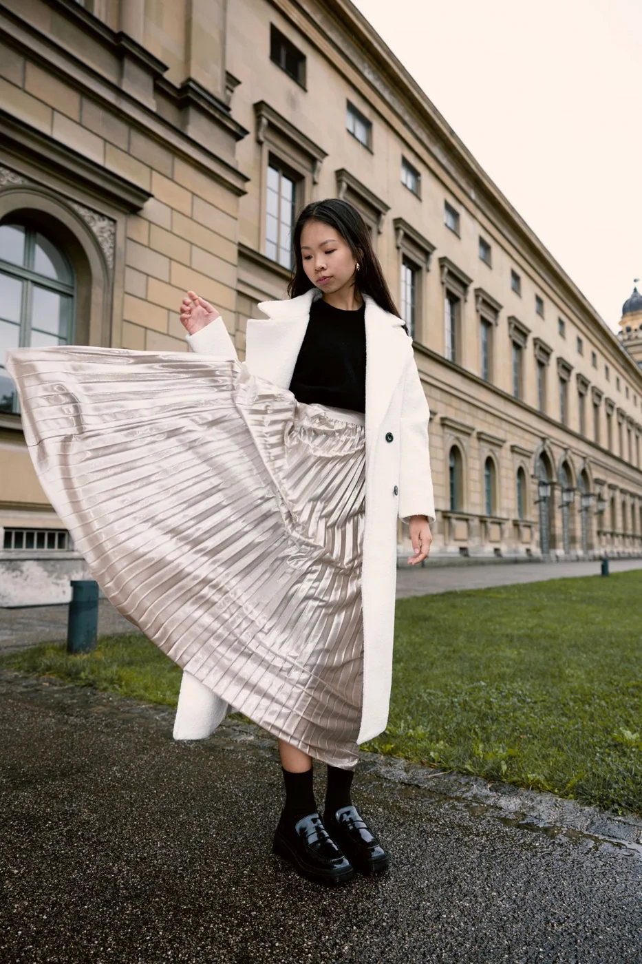 Long pleated skirt beneath a shorter light coat.