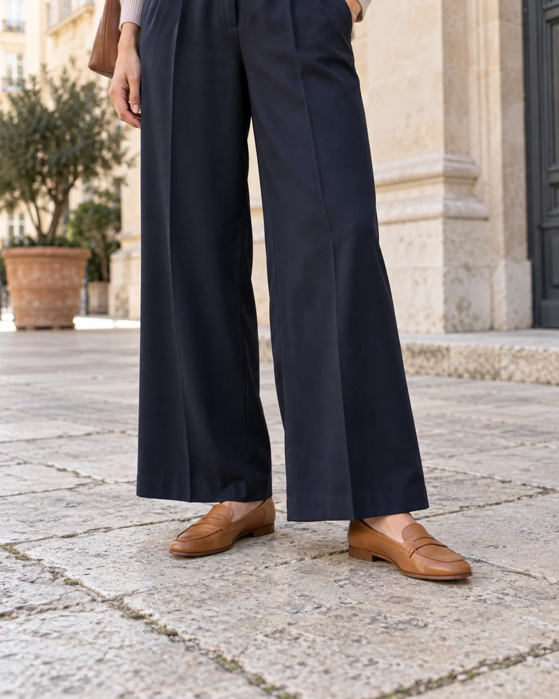 Wide navy trousers with flat loafers.
