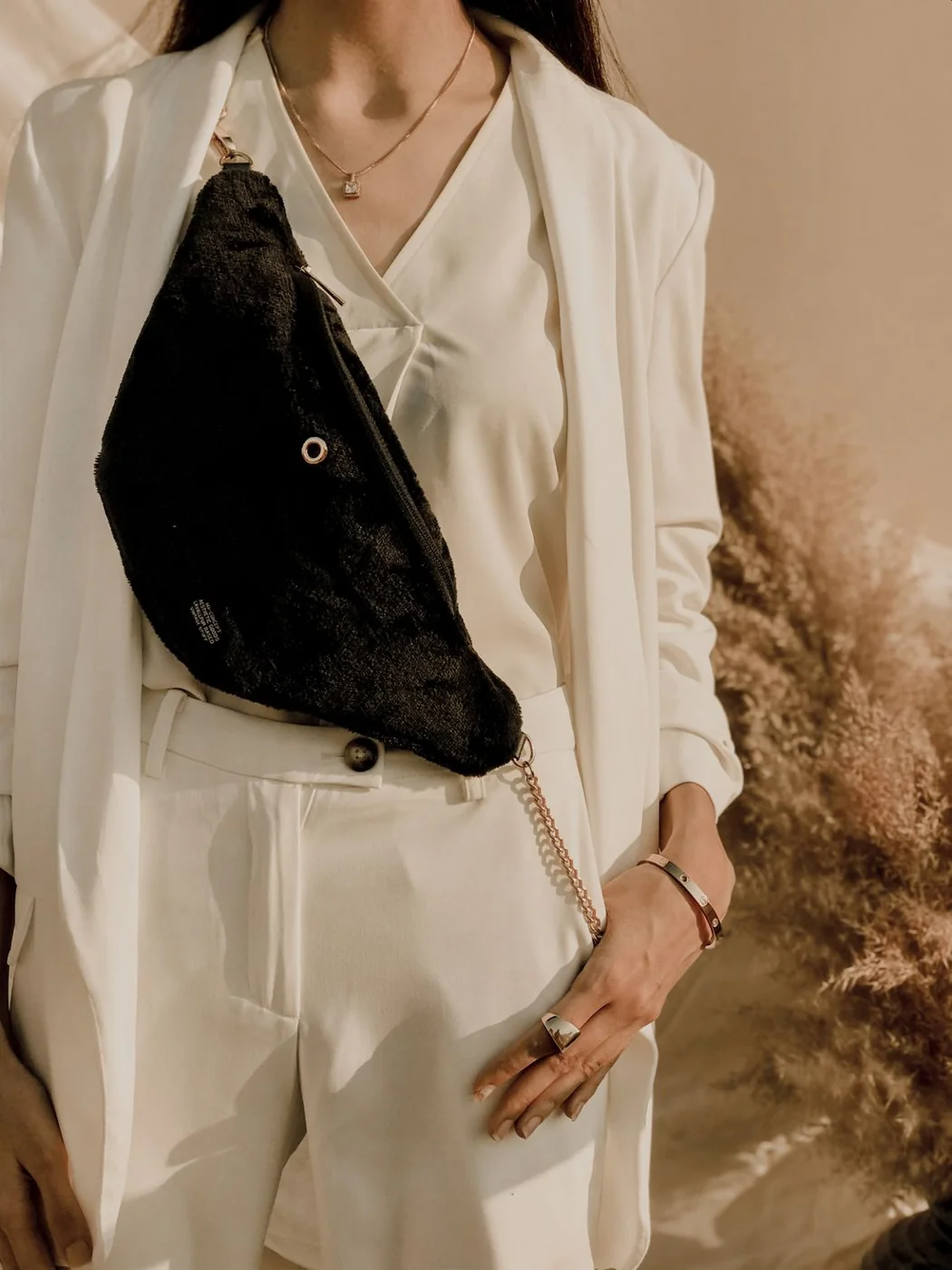 Black crossbody bag worn across a light suit.