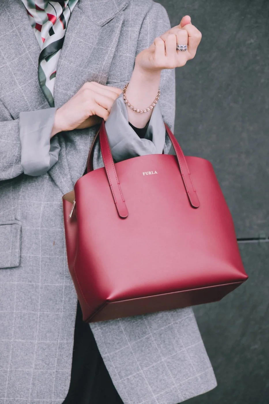 Red handbag against a grey blazer.