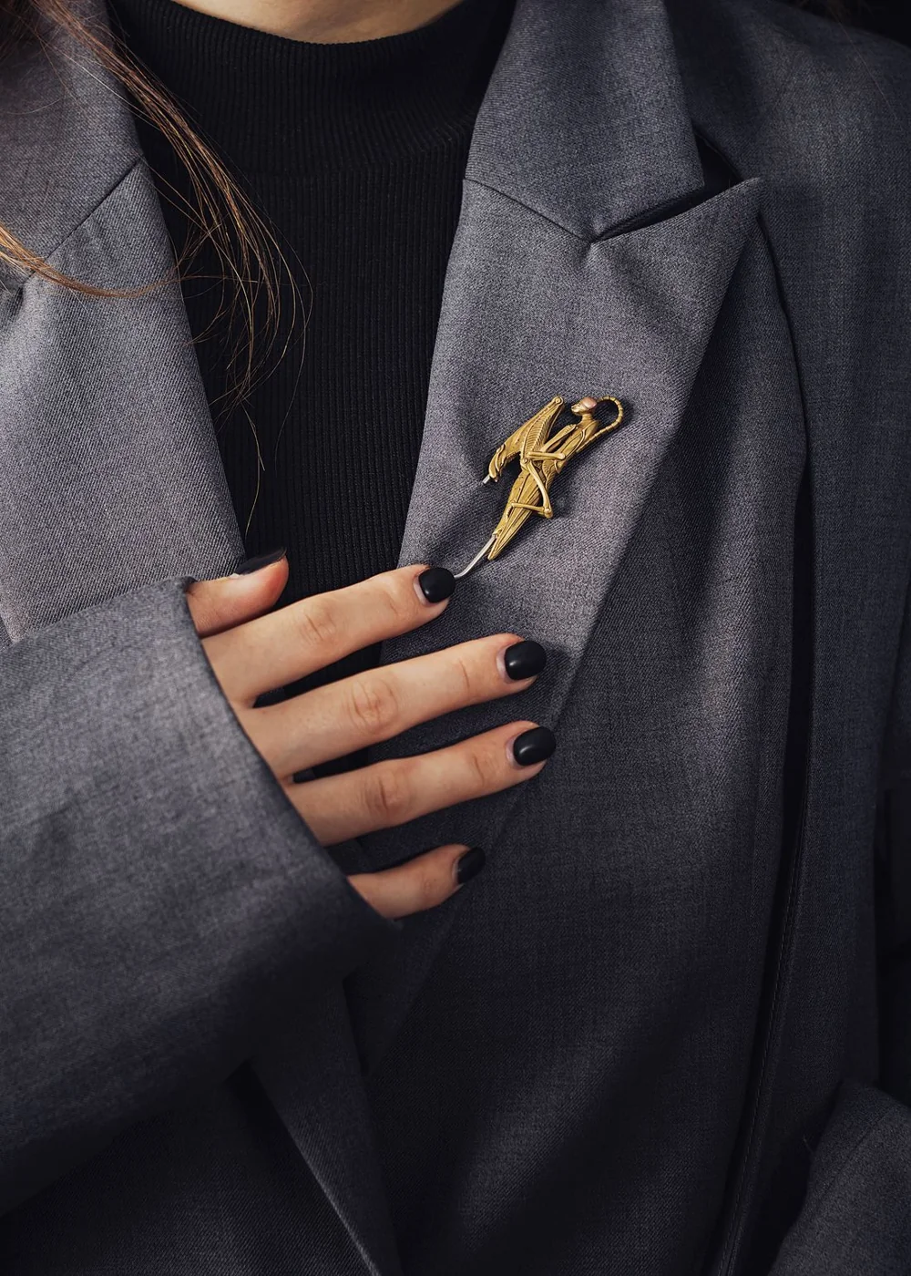 Insect-shaped brooch on a dark blazer lapel.