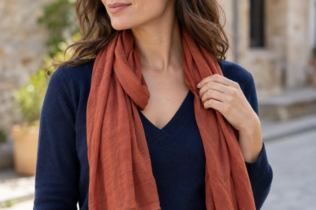 A loosely draped rust scarf over a navy V-neck.