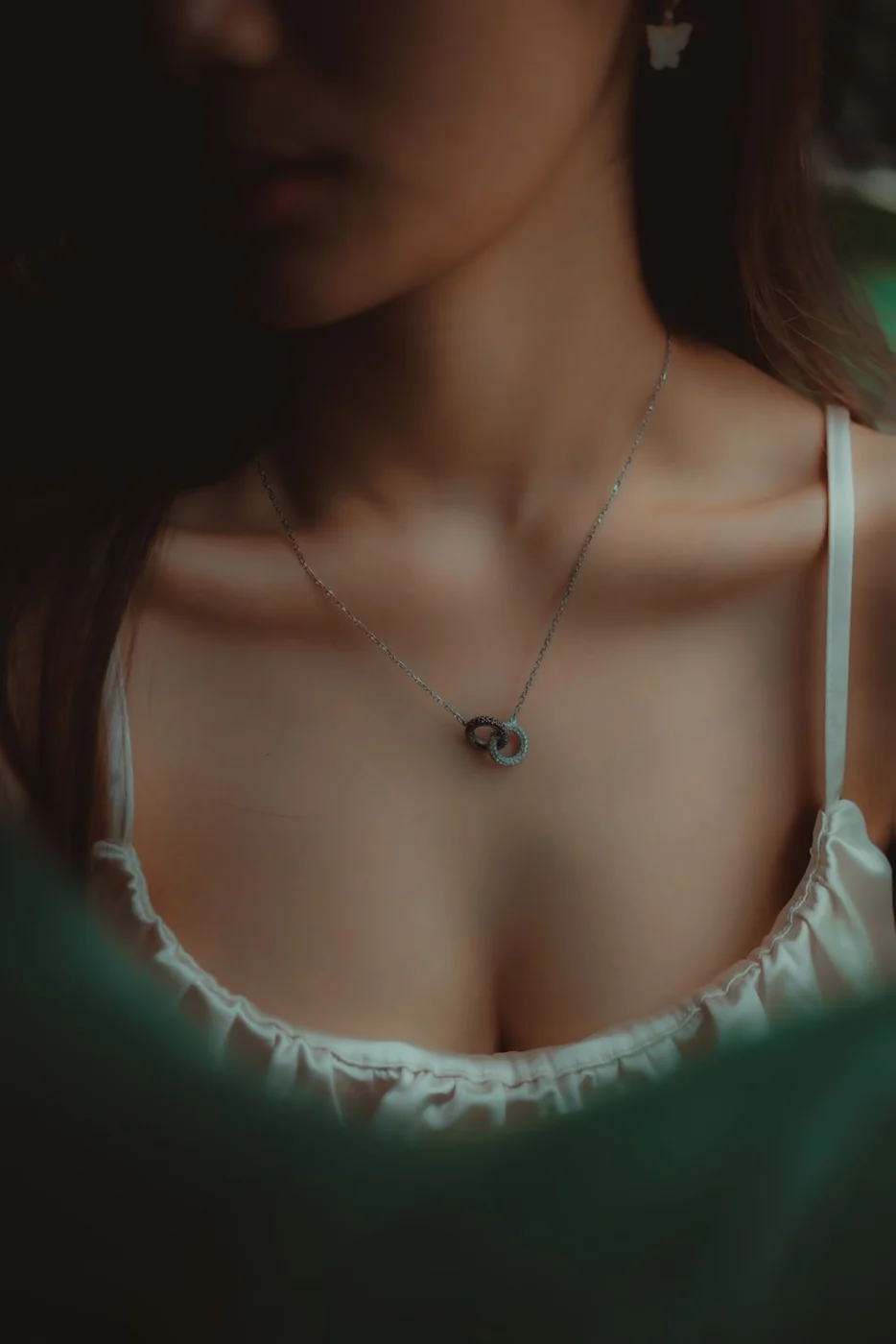 Short necklace above the neckline of a light top.