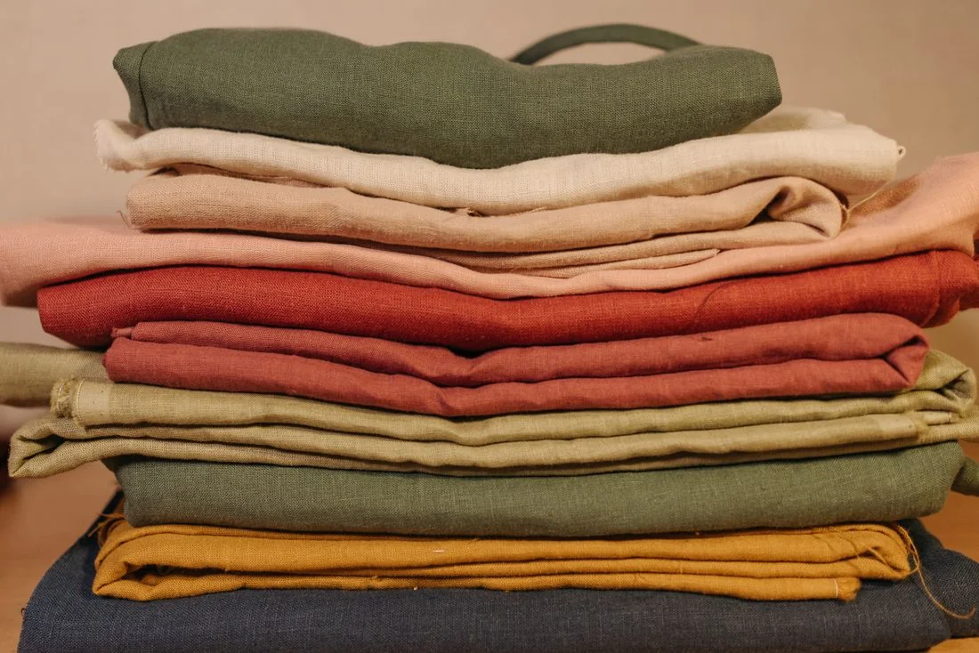 Neatly stacked folded garments in several colours.