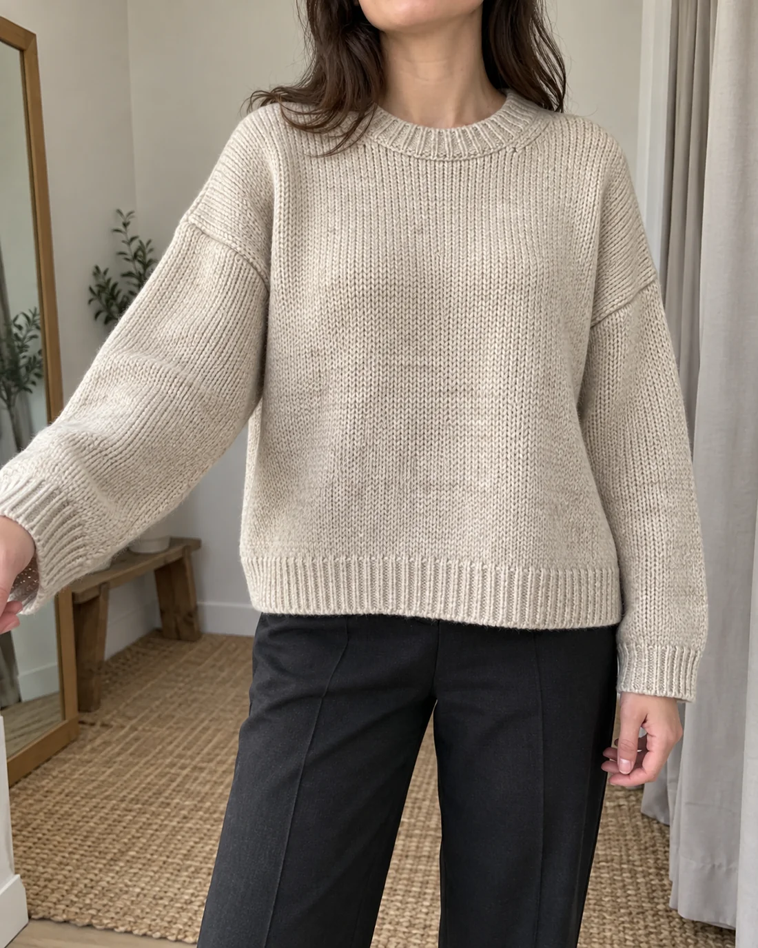 Relaxed pale knitted jumper with dropped shoulders and visible sleeve cuffs.